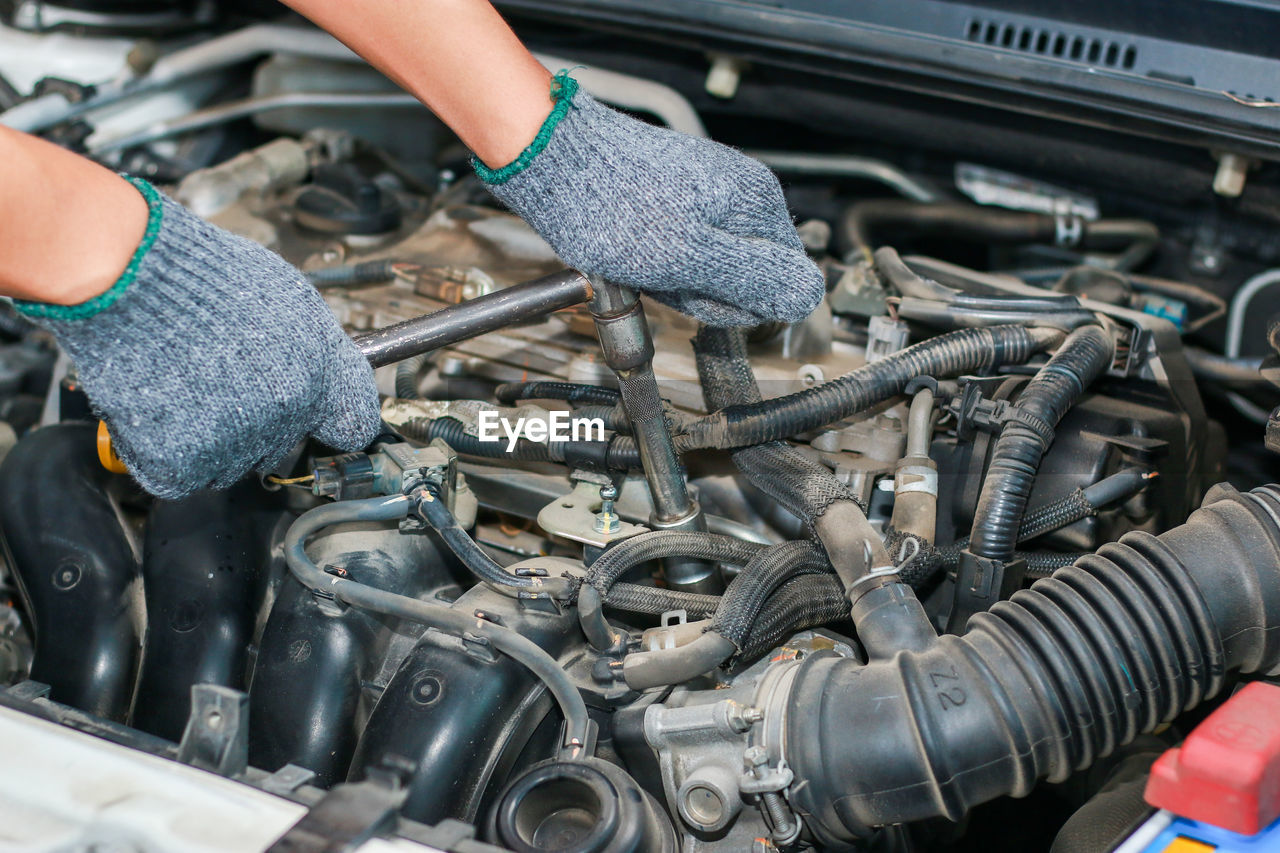 The mechanic is tightening the nut in the engine compartment of the car.