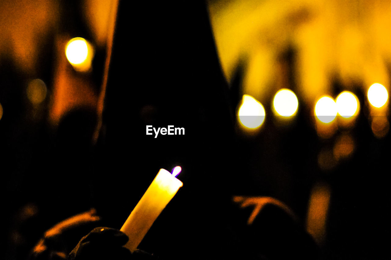 Penitent holding burning candle during holy week at night