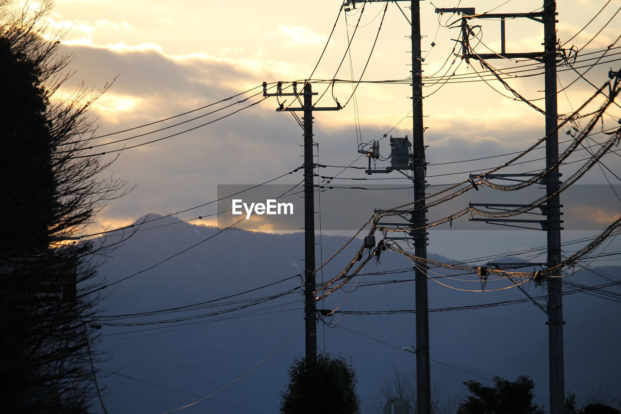 Low angle view of electricity pylon against sky during sunset