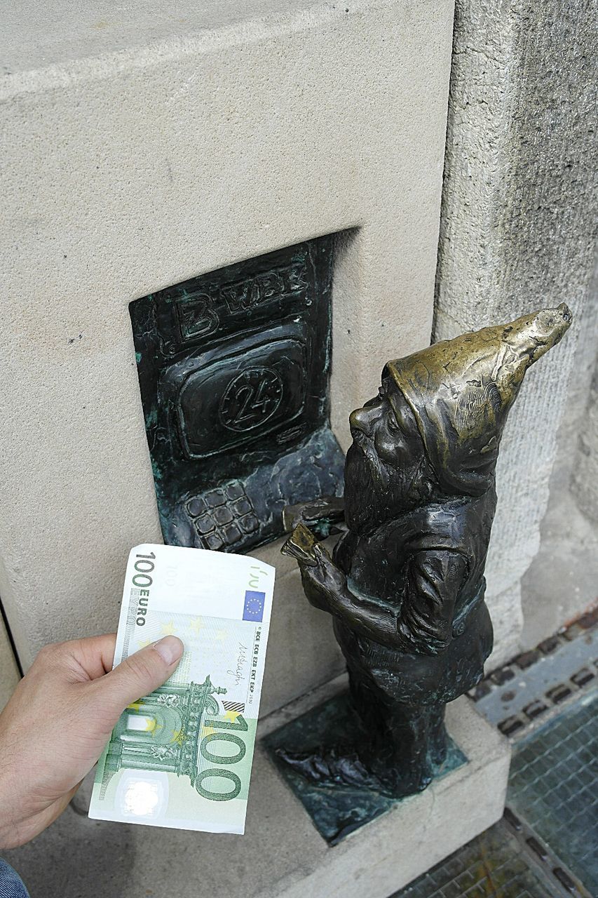 Cropped hand holding paper currency by figurine