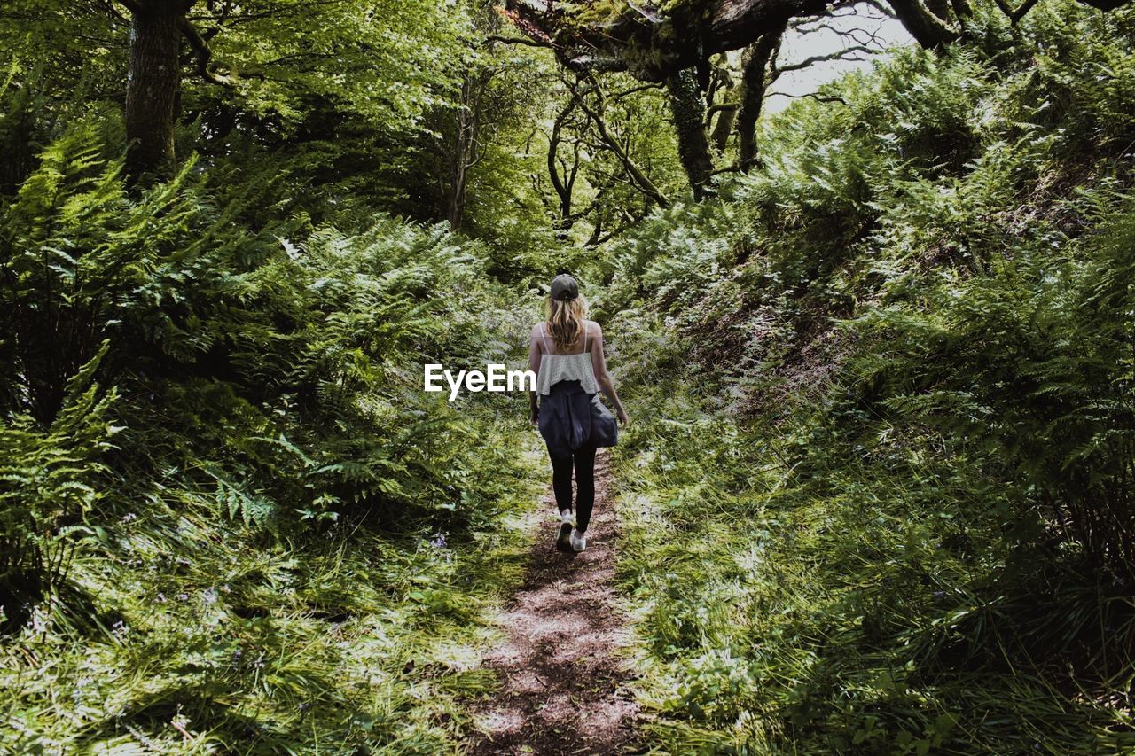 Young woman walking amidst trees in forest