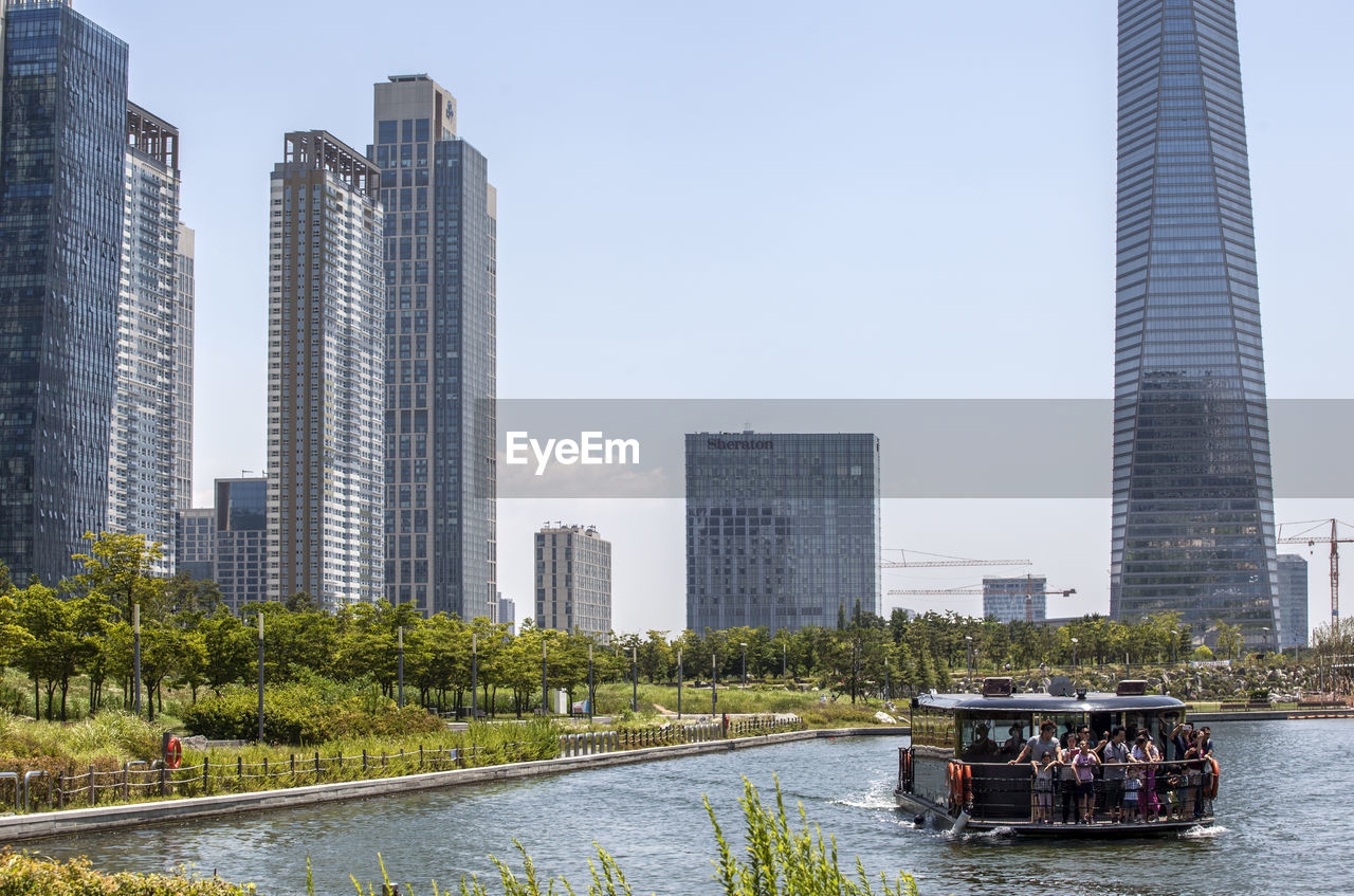 People enjoying in boat over lake against buildings