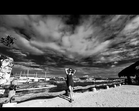 WOMAN STANDING ON BEACH AGAINST CLOUDY SKY