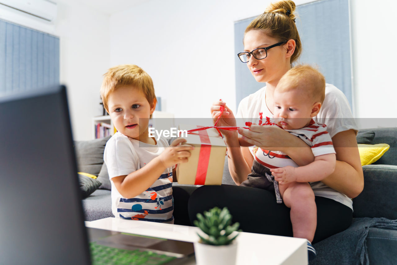 FRIENDS LOOKING AT CAMERA WHILE SITTING ON LAPTOP