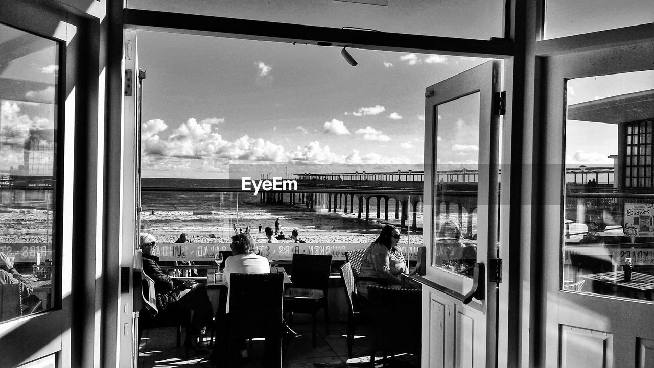 People sitting on sidewalk cafe seen through doorway