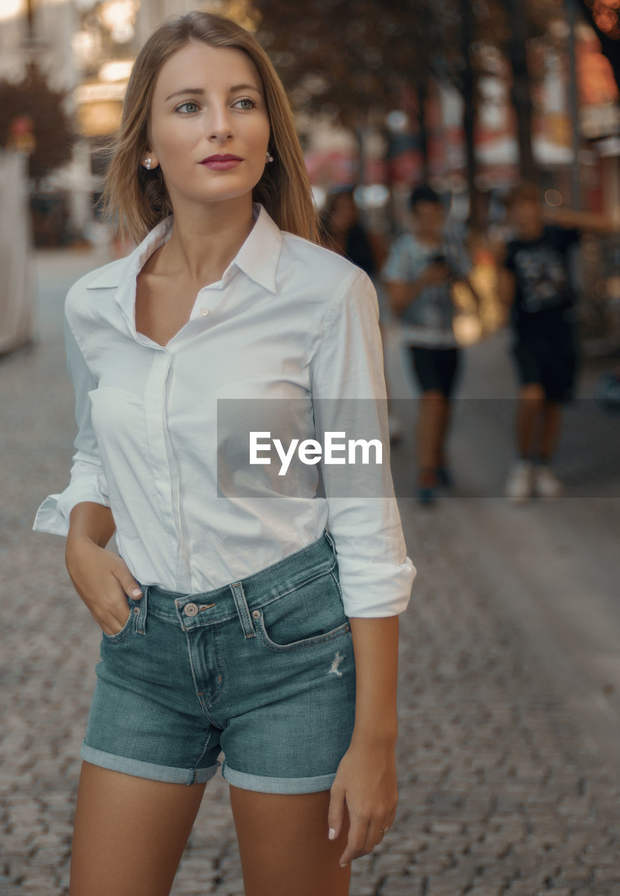 Portrait of young woman standing in city