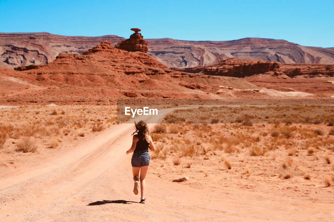 Rear view of teenage girl running at desert