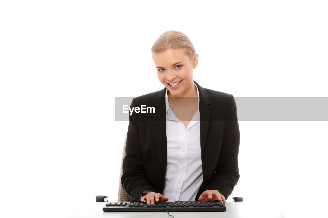 Businesswoman working at desk against white background