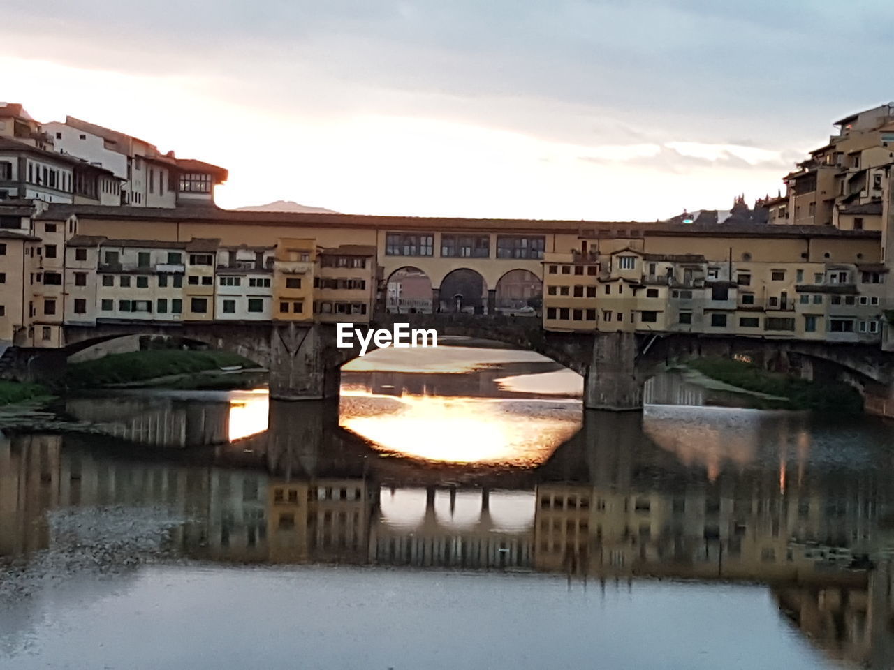 ARCH BRIDGE OVER RIVER BY BUILDINGS AGAINST SKY