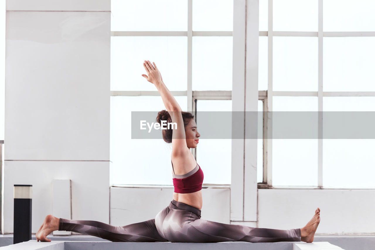 Woman exercising on railing against window