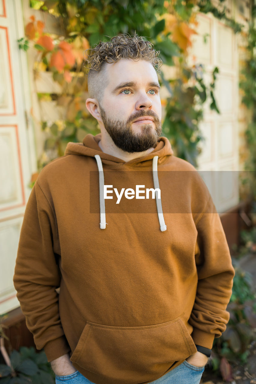 portrait of young man looking away while standing outdoors