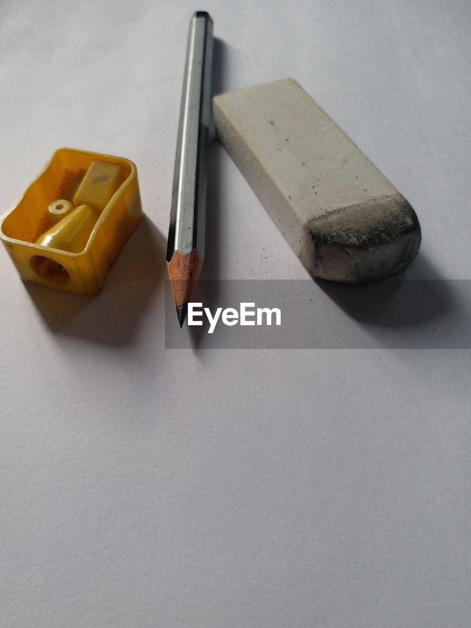 High angle view of pencil with eraser and sharpener on white background
