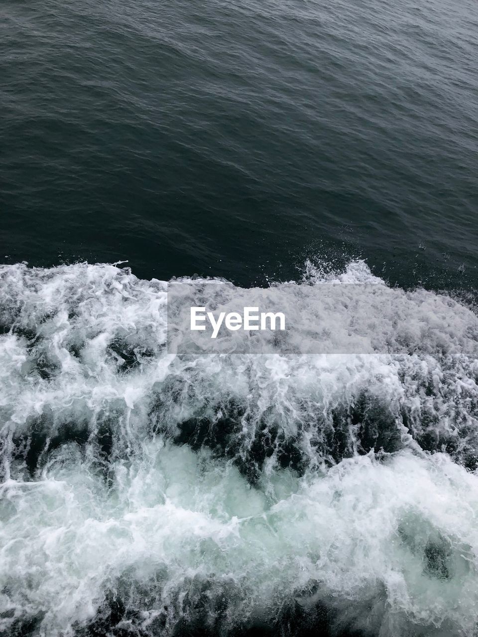 HIGH ANGLE VIEW OF WAVES SPLASHING ON SEA