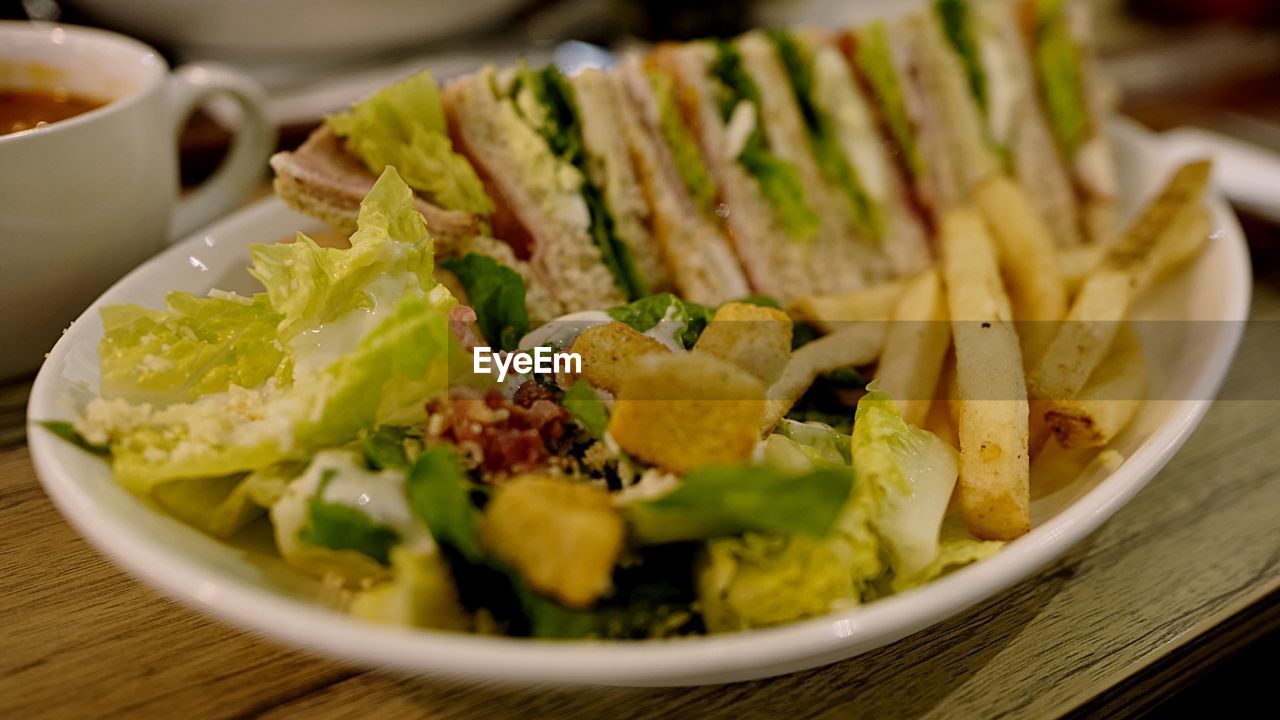 Close-up of sandwiches with french fries served in bowl on table