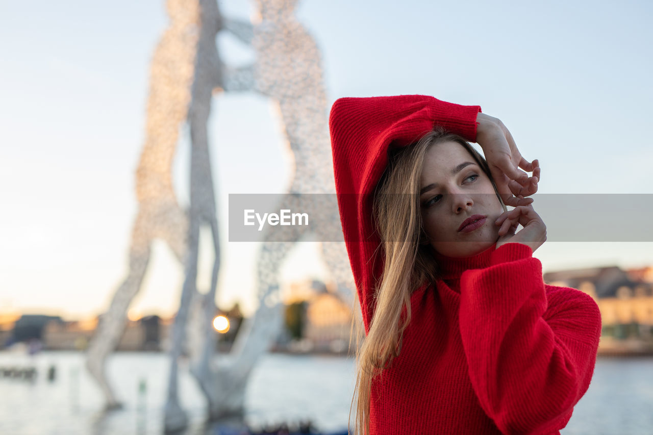 Beautiful young woman looking away against sky