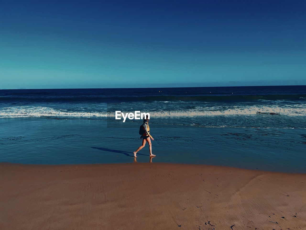 FULL LENGTH OF MAN AT BEACH AGAINST BLUE SKY