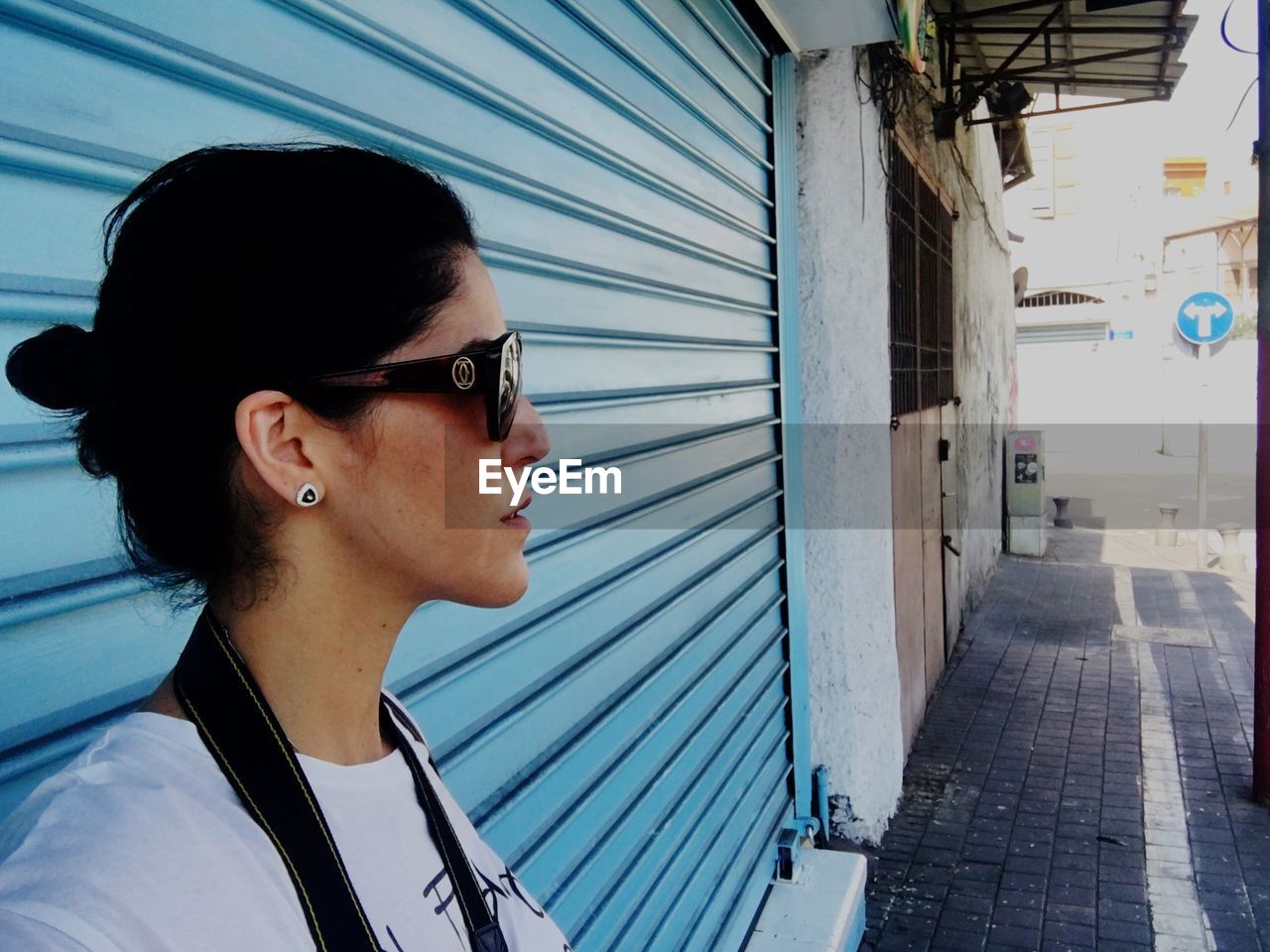 Woman in sunglasses standing against shutter