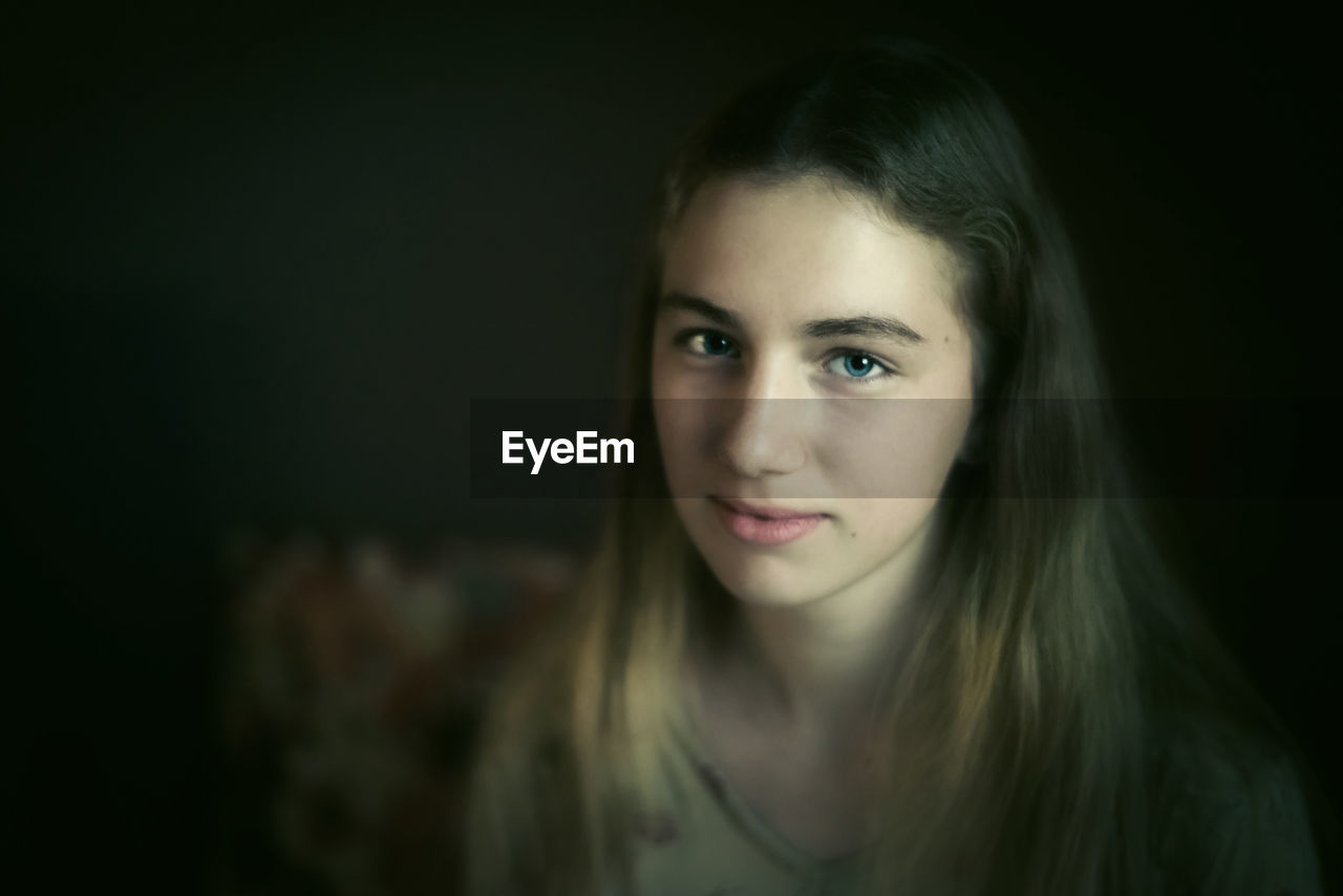 CLOSE-UP PORTRAIT OF BEAUTIFUL YOUNG WOMAN OVER BLACK BACKGROUND