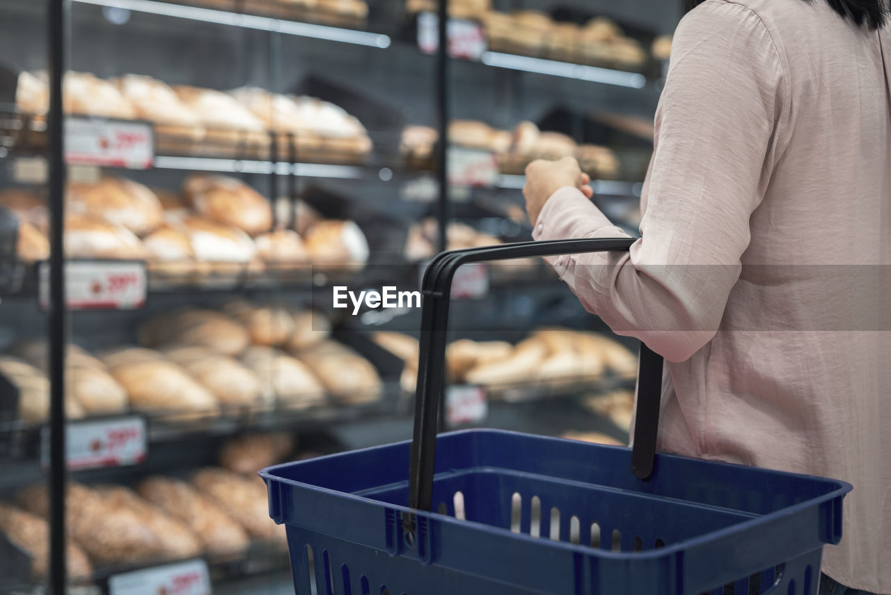Woman with shopping basket in bakery section of supermarket
