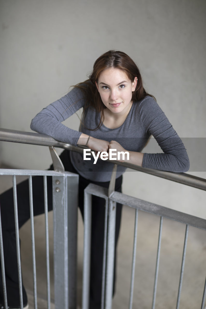 High angle view portrait of woman standing by railing on staircase