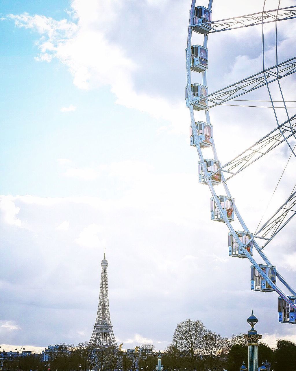 Low angle view of ferris wheel against eiffel tower in city