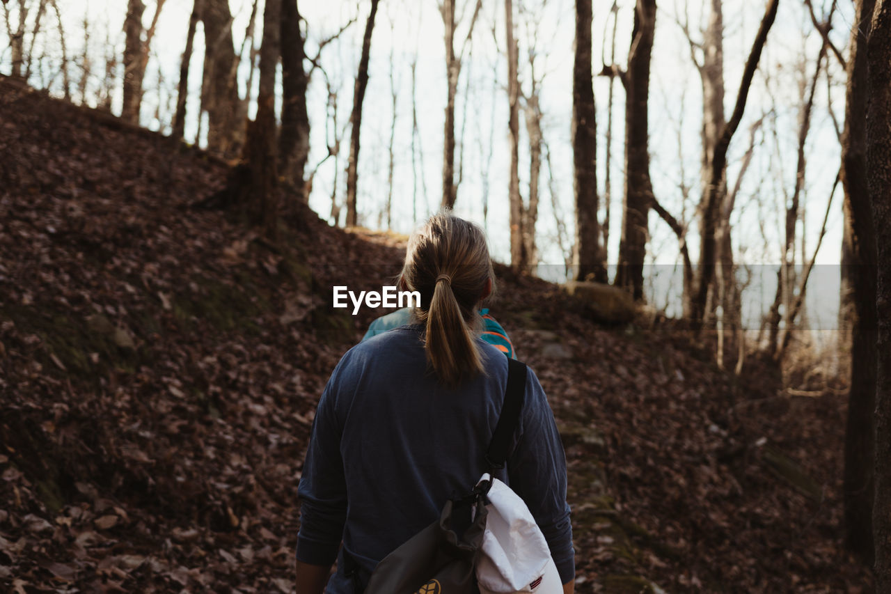 REAR VIEW OF WOMAN STANDING BY AUTUMN TREE