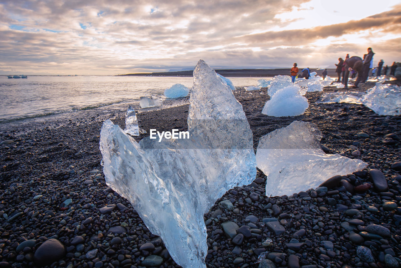 Icebergs at sea shore against sky