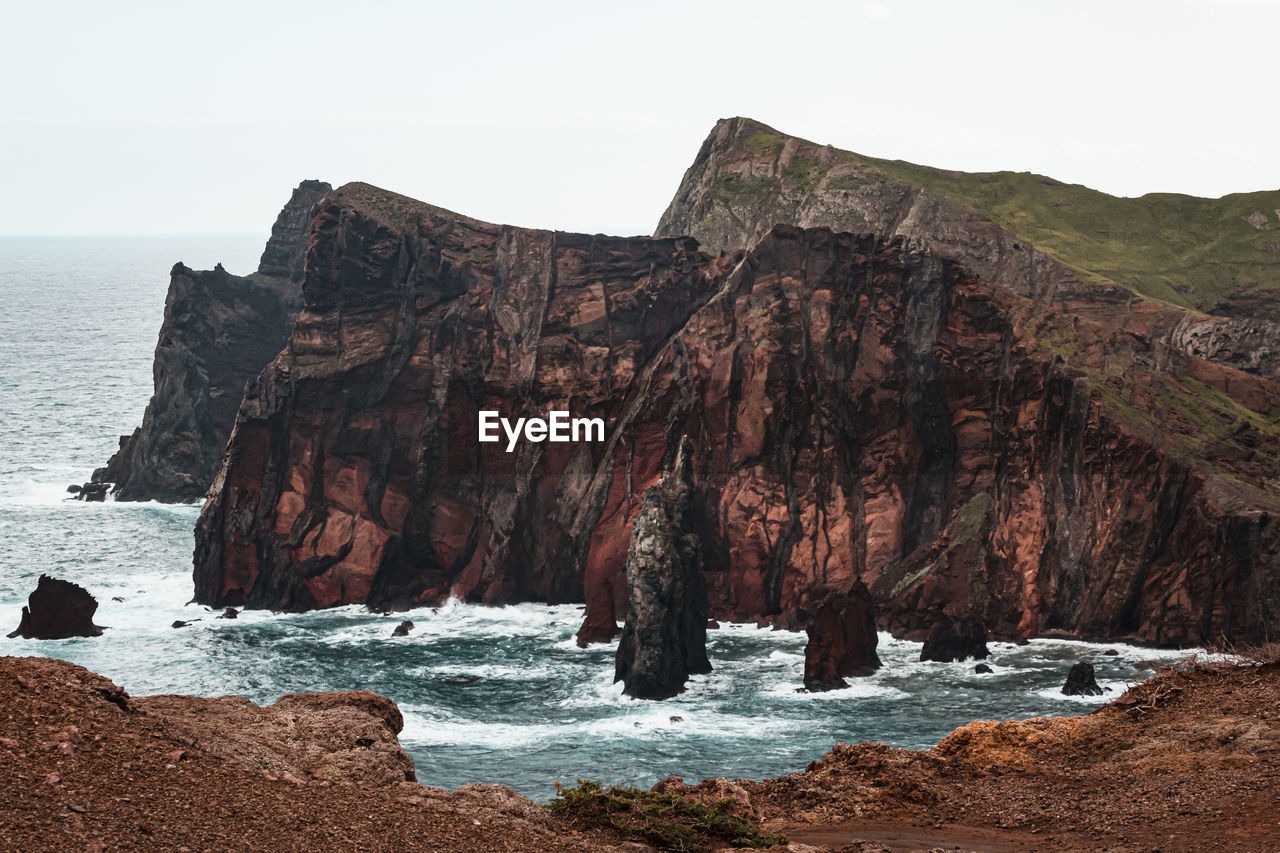 Rock formation by sea against clear sky