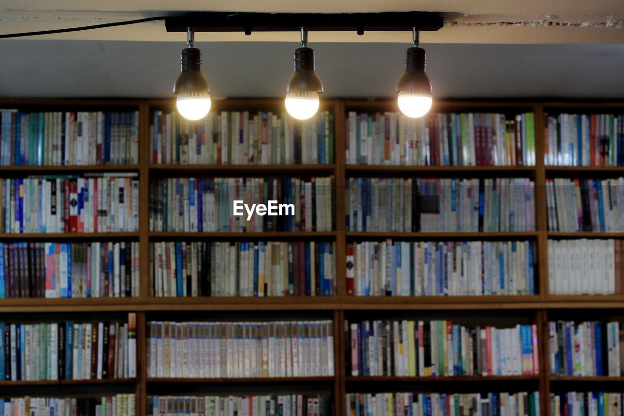 Illuminated lights with books in shelves in background