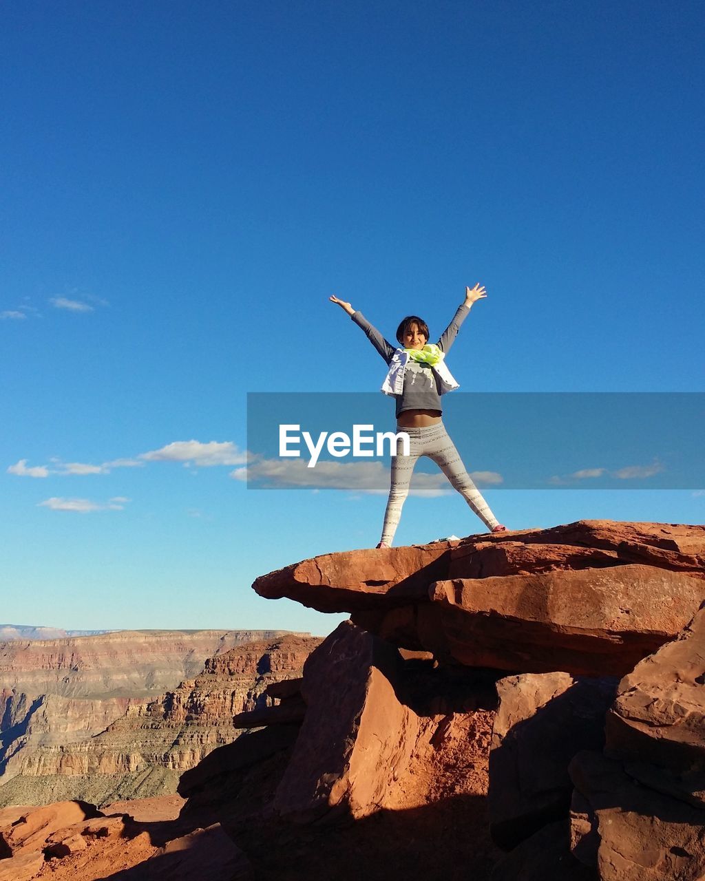 Woman standing on rock by canyon