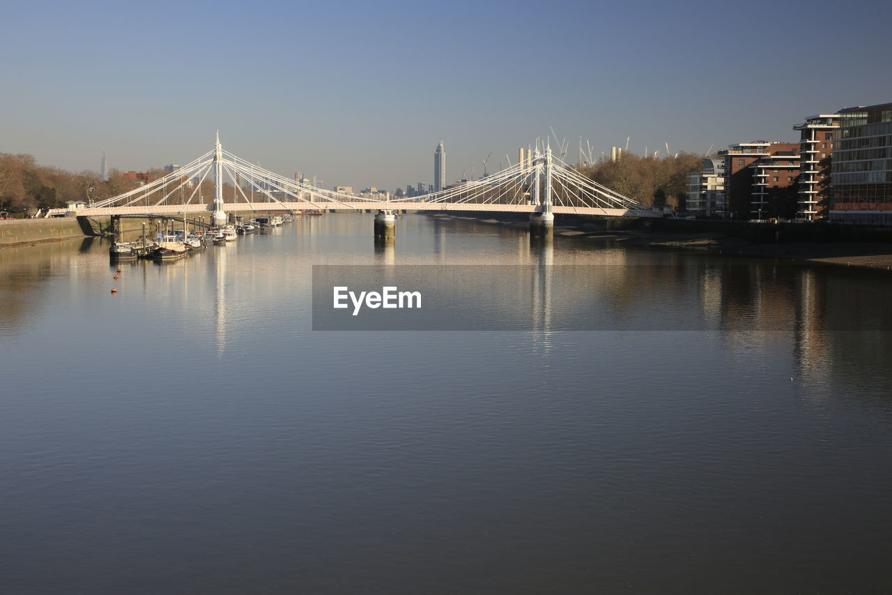 Bridge over river against sky in city