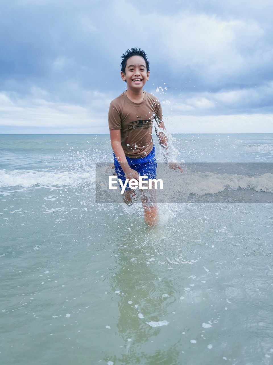 Portrait of young boy in sea against sky