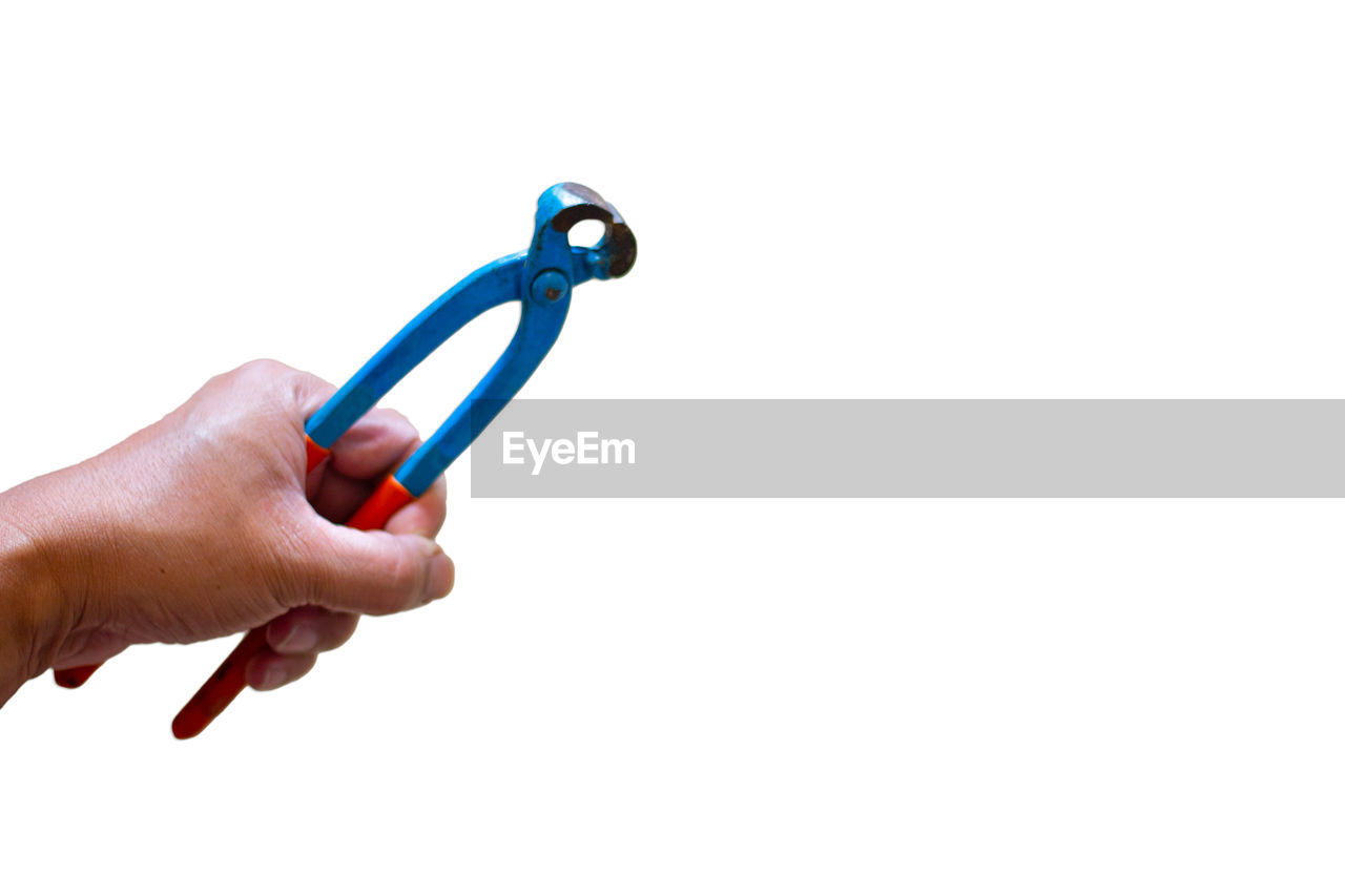 Close-up of hand holding pliers over white background