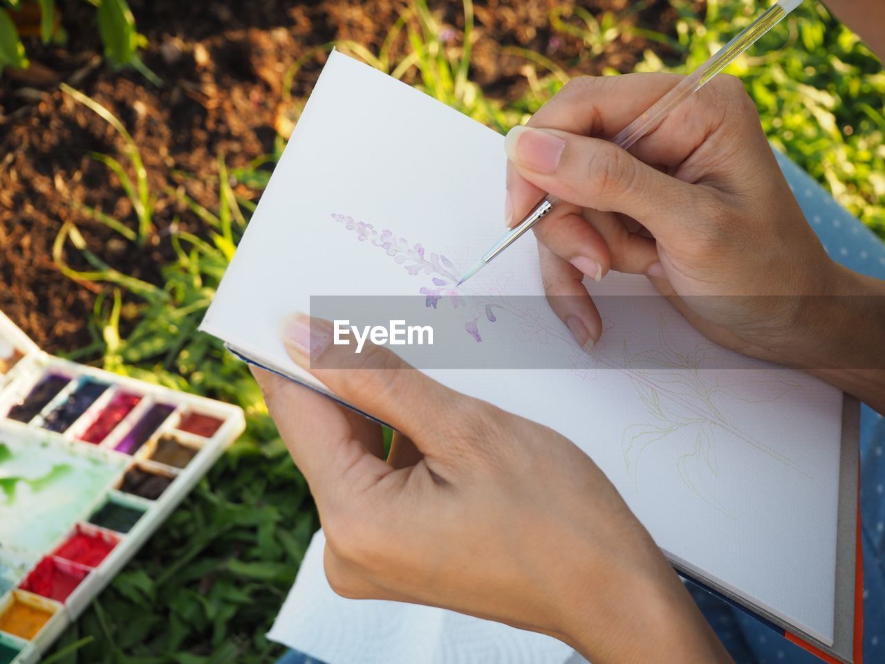 High angle view of woman hand painting on paper in park