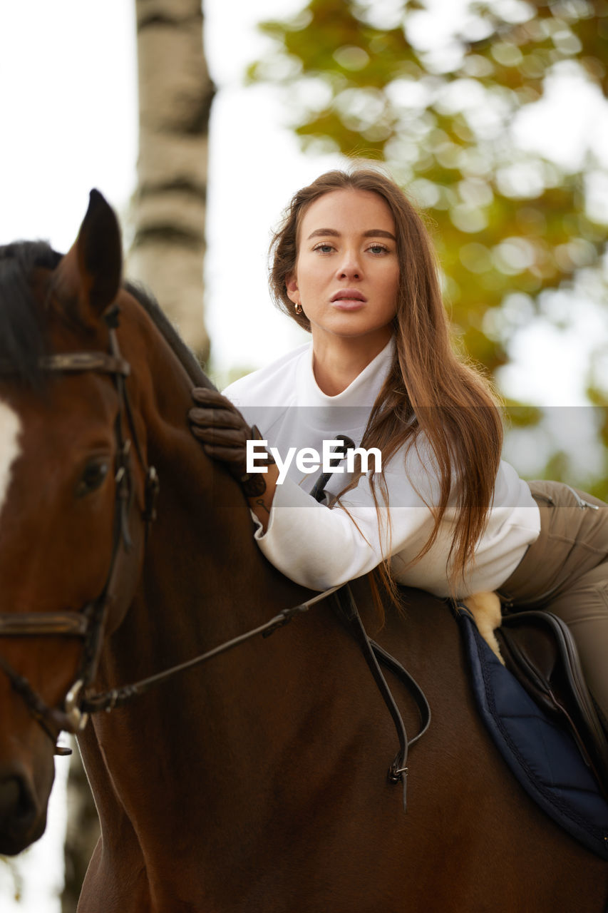 portrait of young woman with horse in park