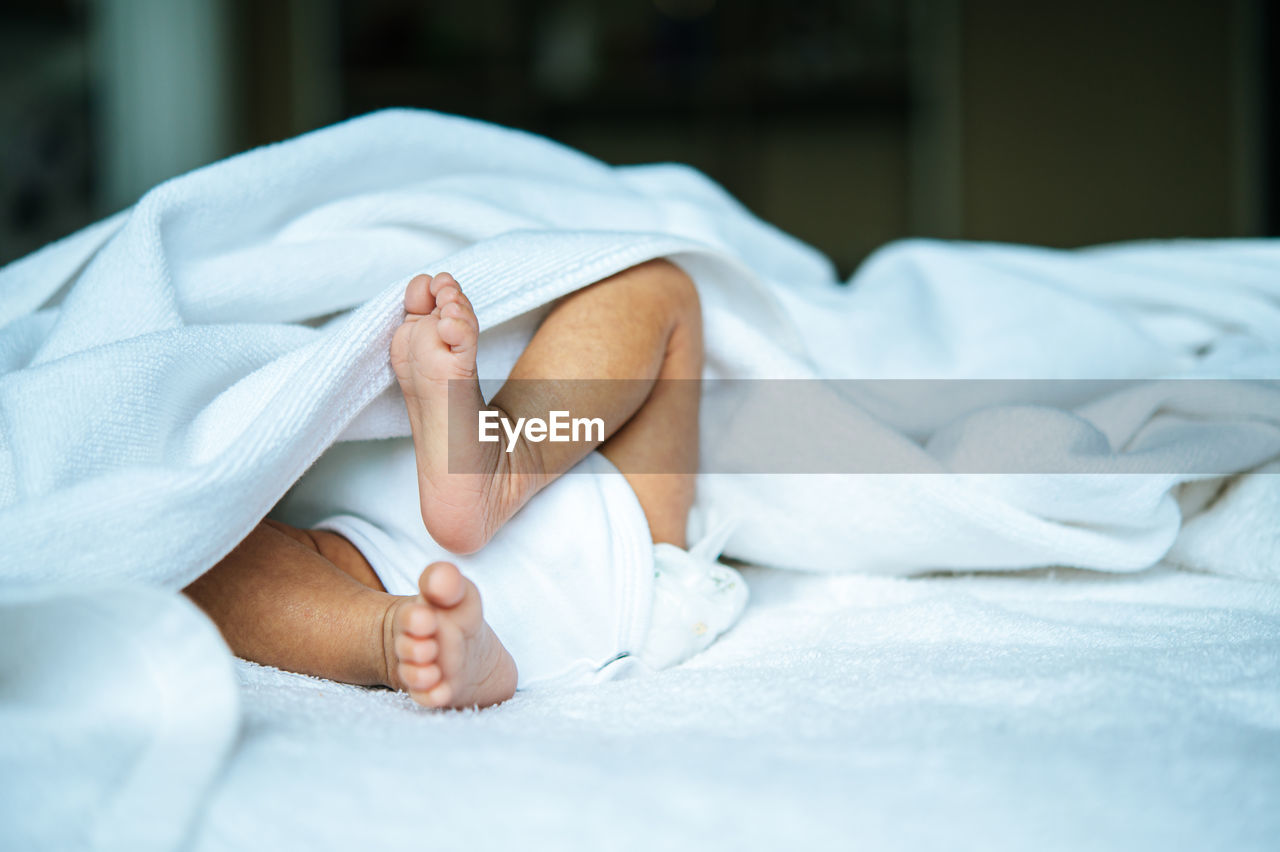 Low section of baby feet on bed