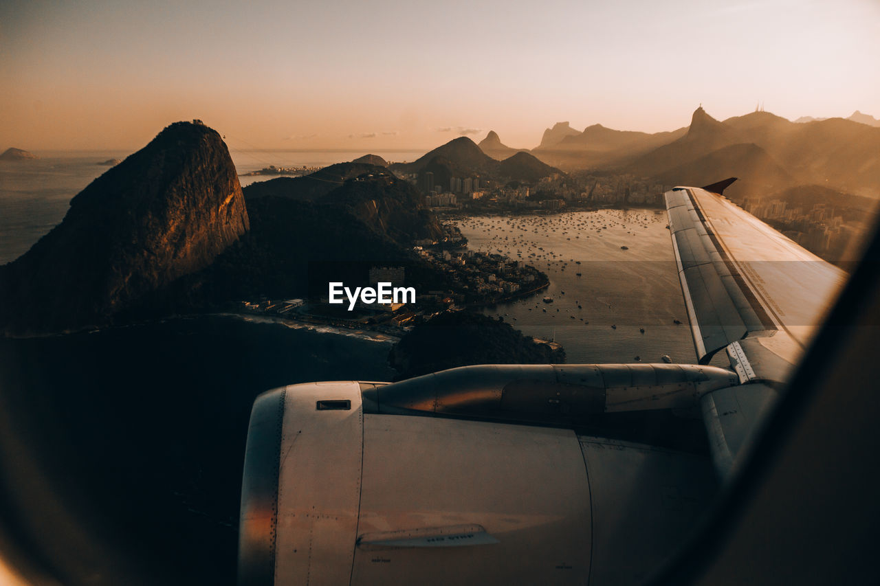 Airplane in mountains against sky during sunset