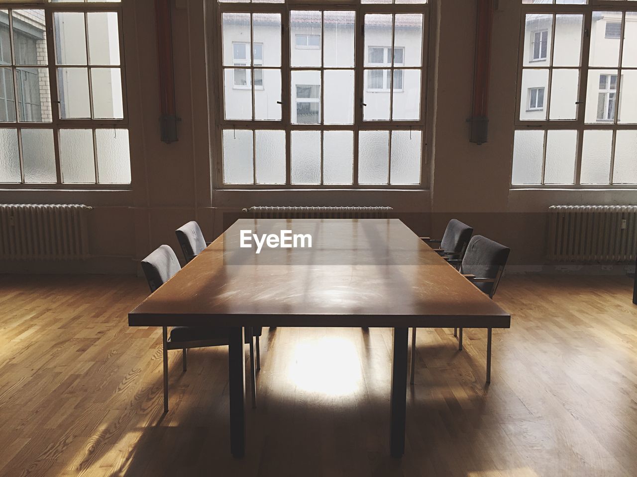Empty table and chairs on hardwood floor in meeting room