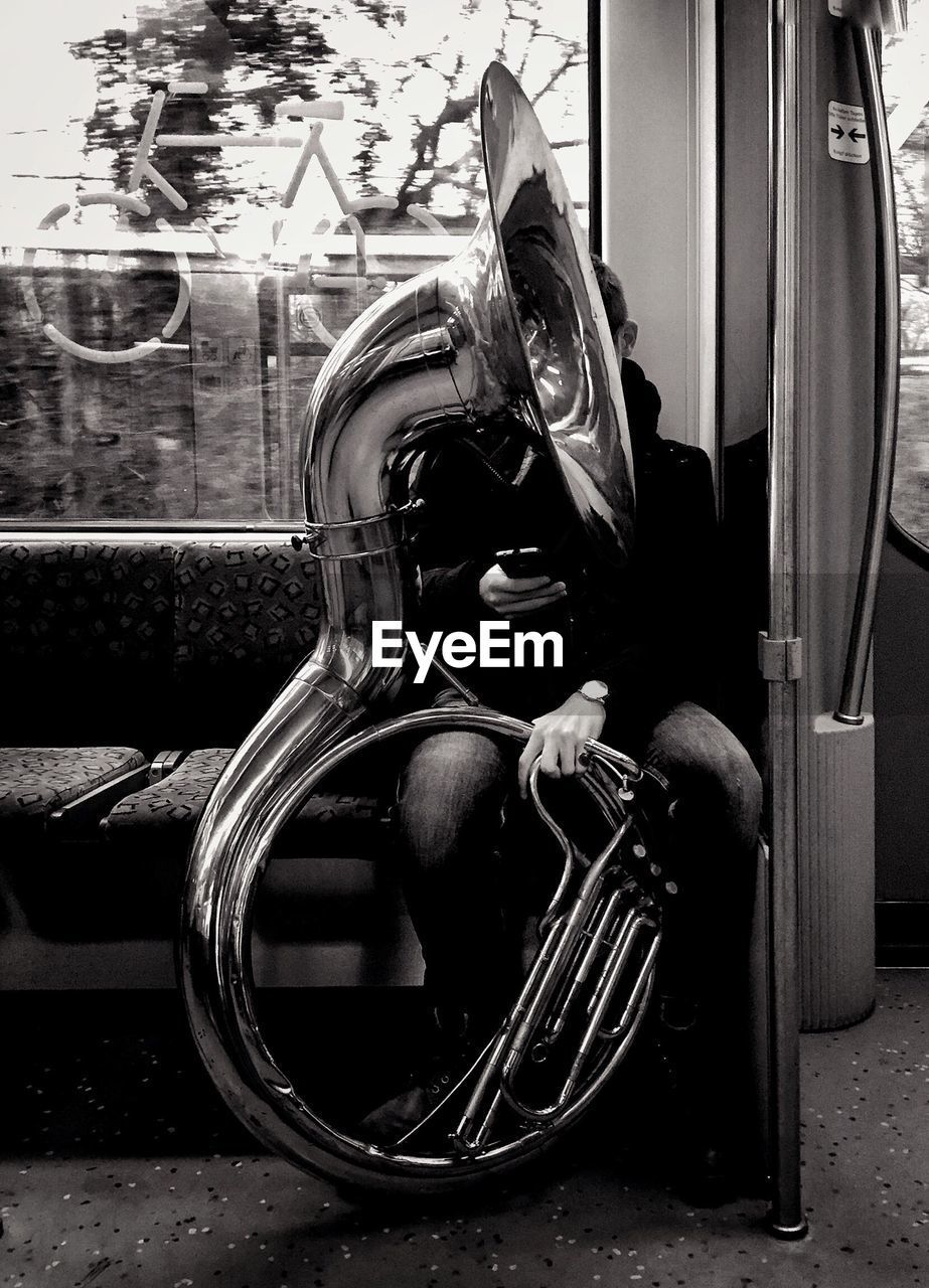 Man sitting with sousaphone in train