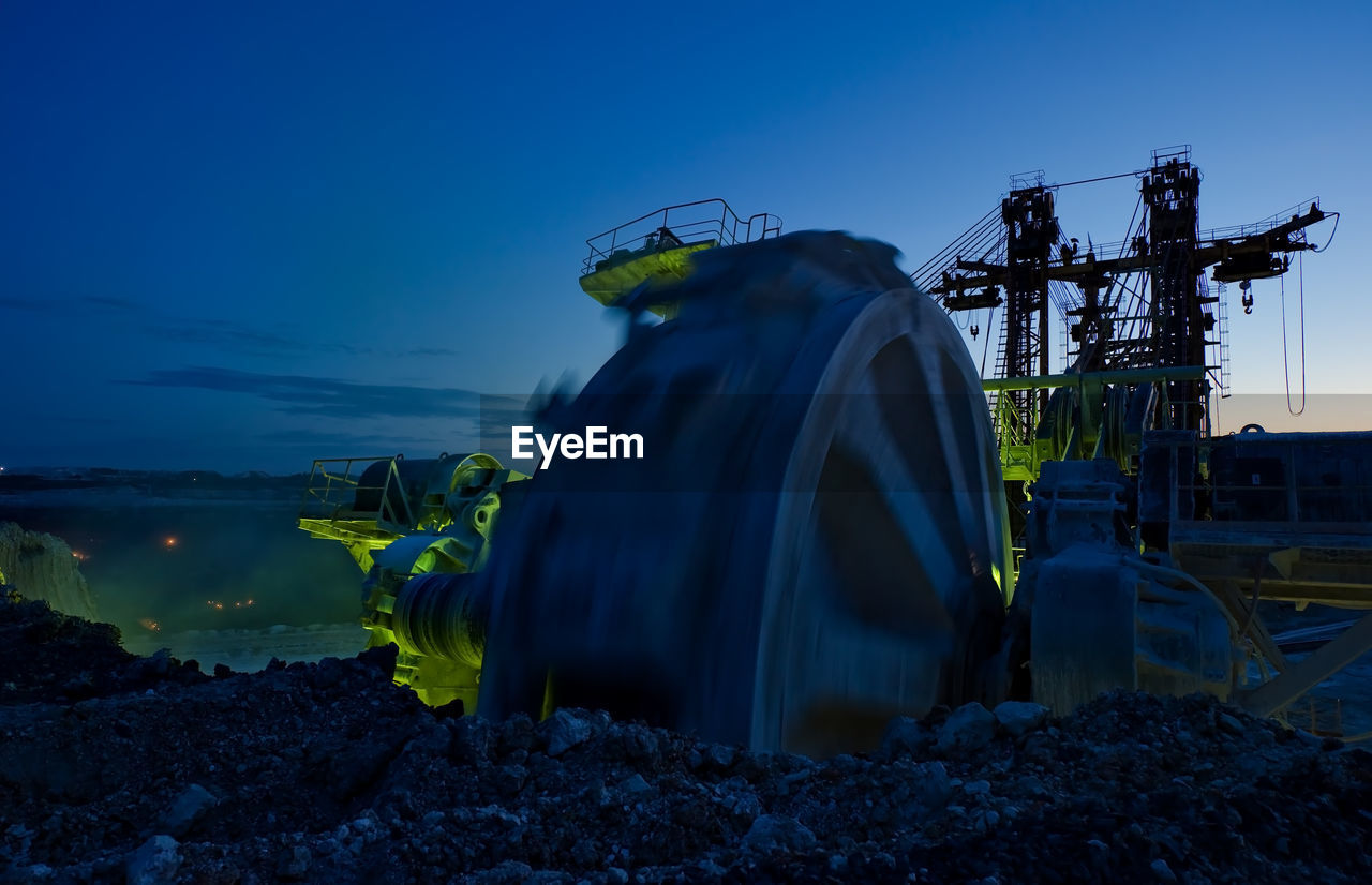 Bucket-wheel excavator at open-pit mine against sky at dusk