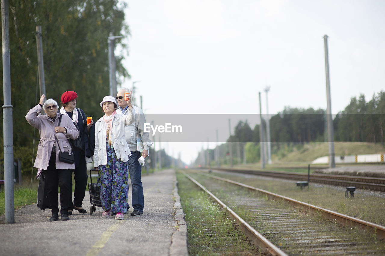 Group of positive elderly seniors old people waiting train before traveling during a pandemic