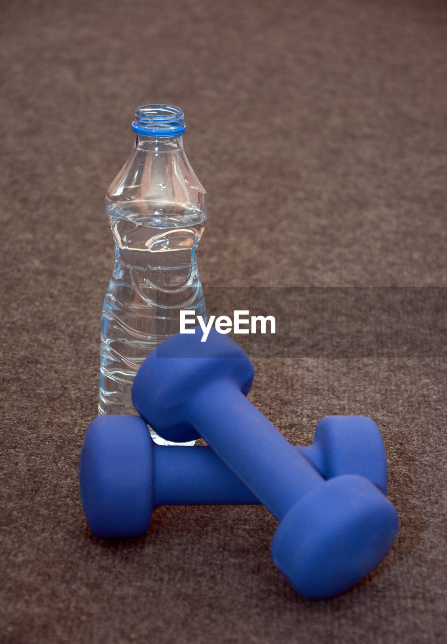 Close-up of blue dumbbells with water bottle