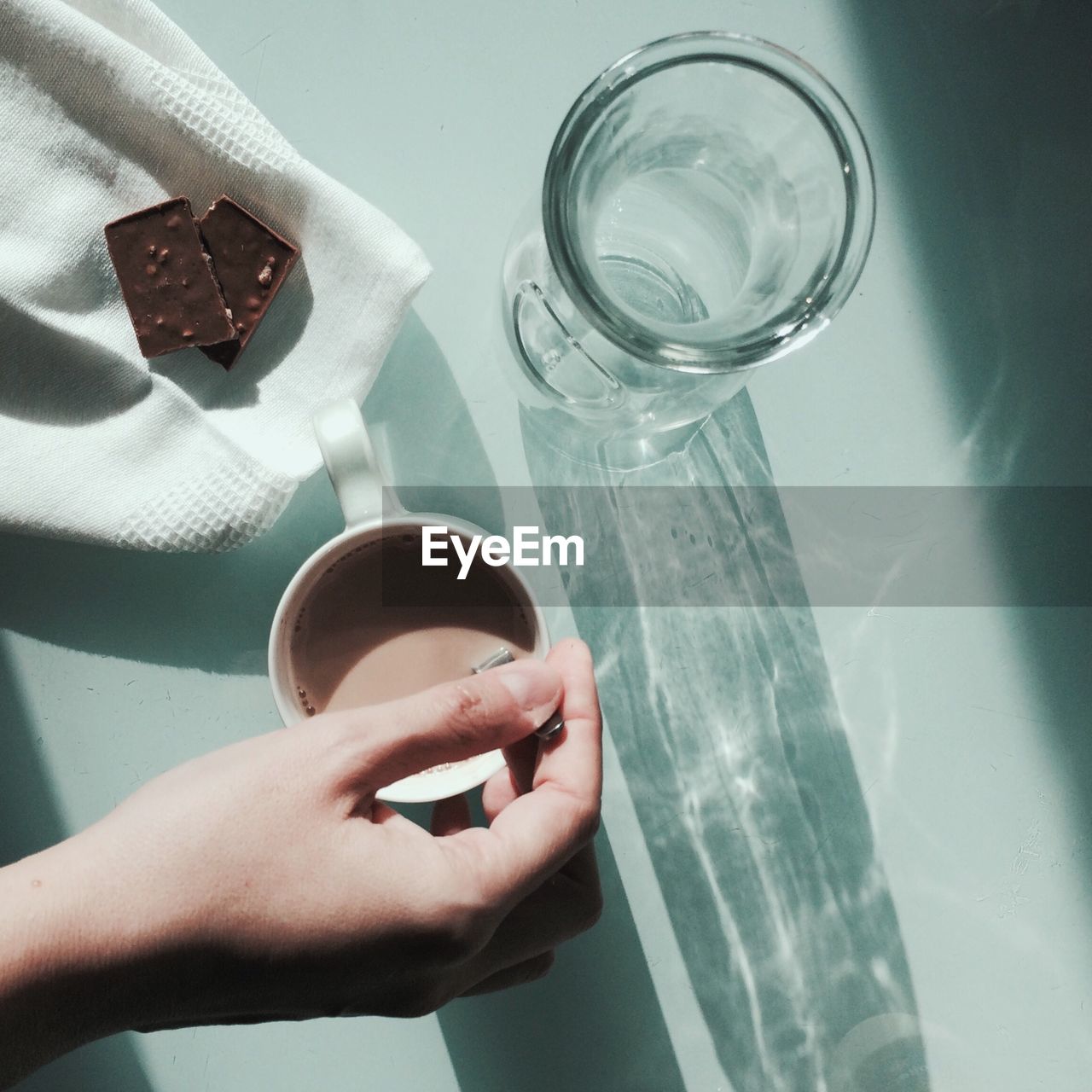 High angle view of hand holding spoon in coffee at table