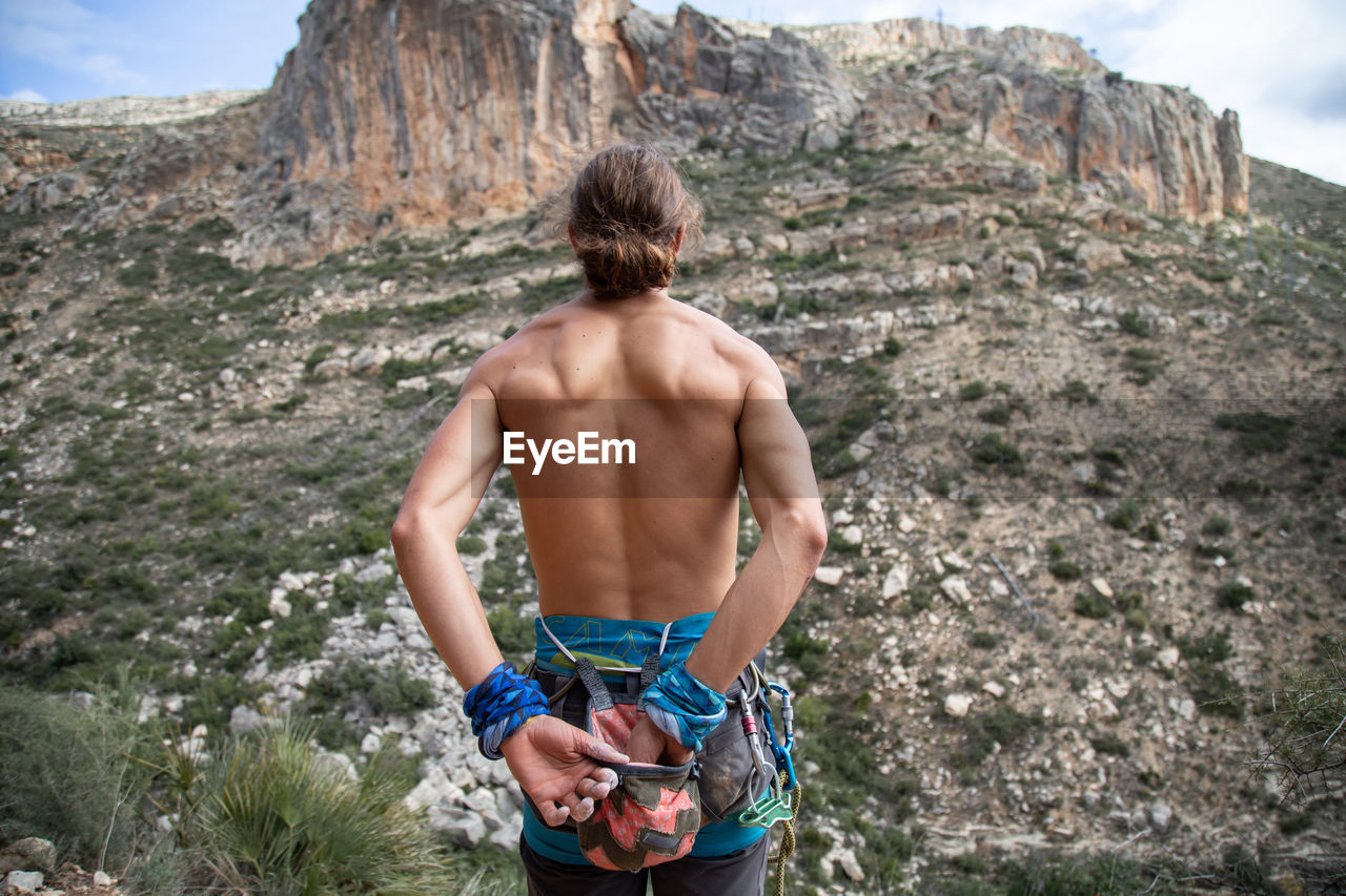 Rear view of shirtless muscular man looking at mountains