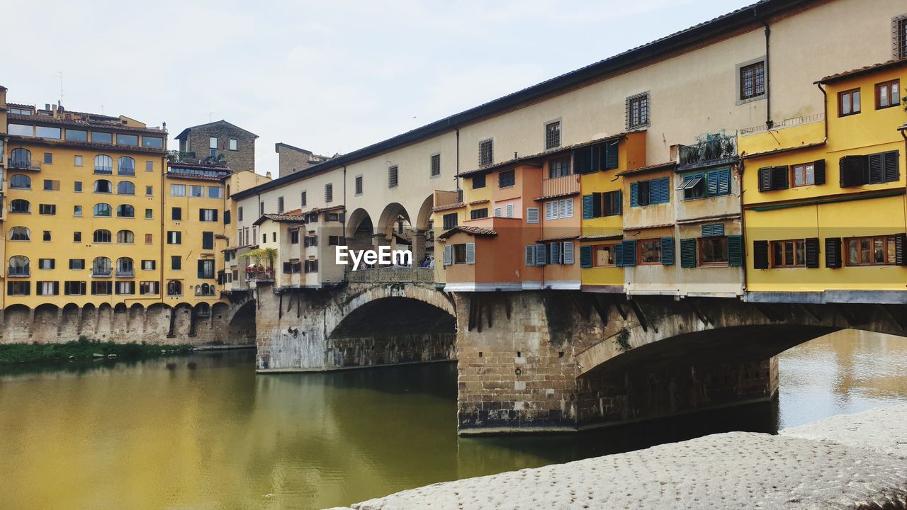 Bridge over river by buildings against sky in florenz