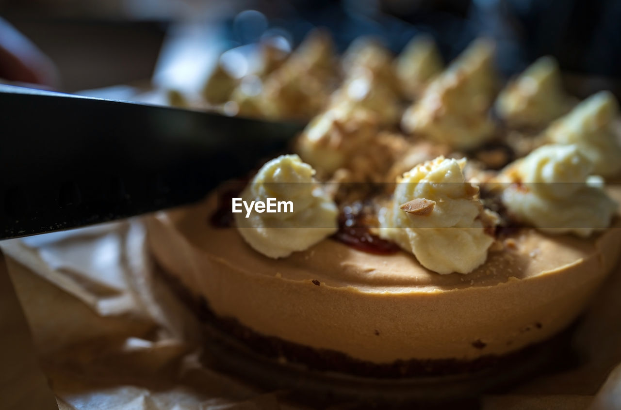 A knife cutting a sweet toffee caramel cake with nuts served as dessert, birthday celebration