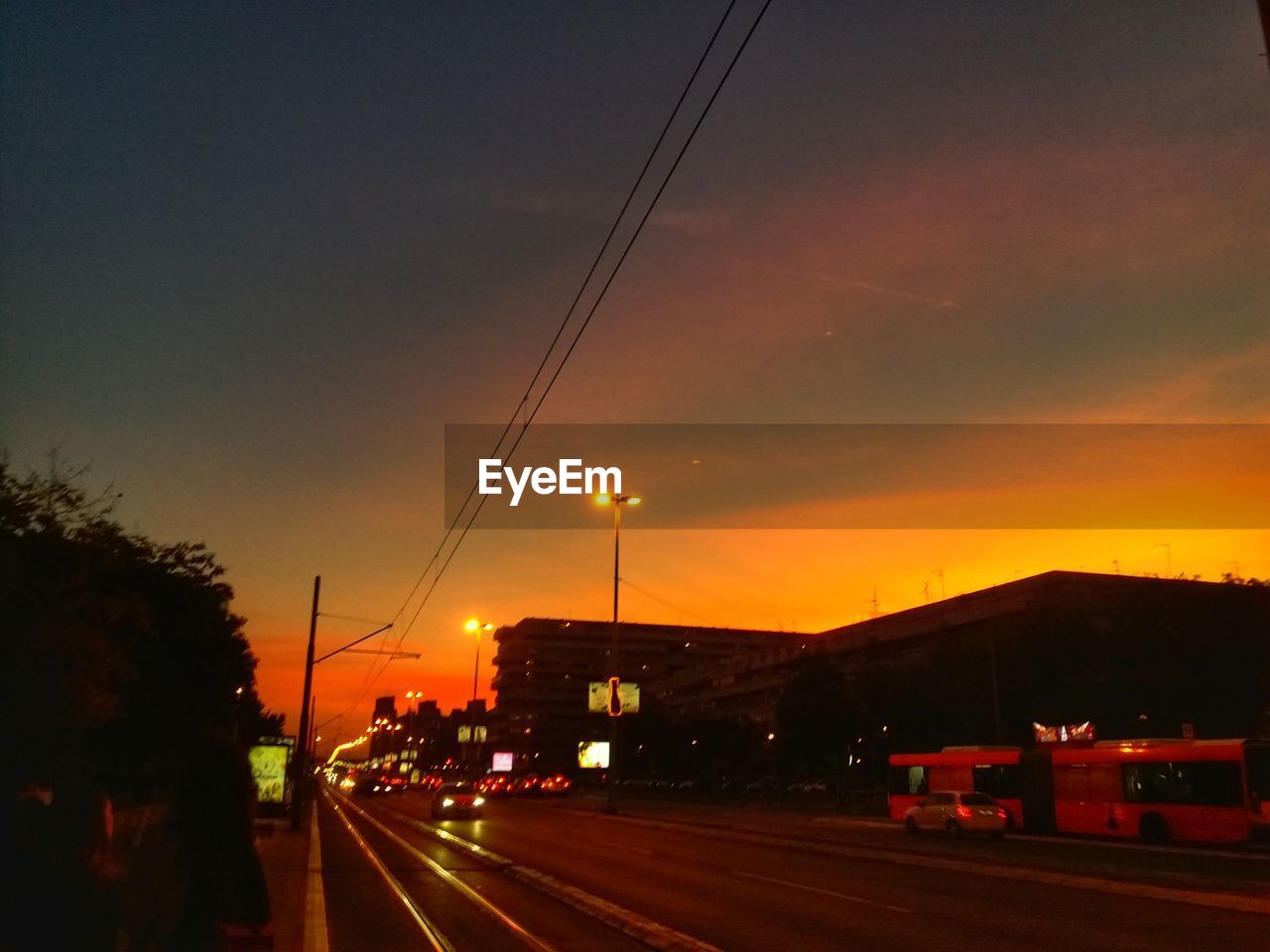 Cars on road against sky at sunset