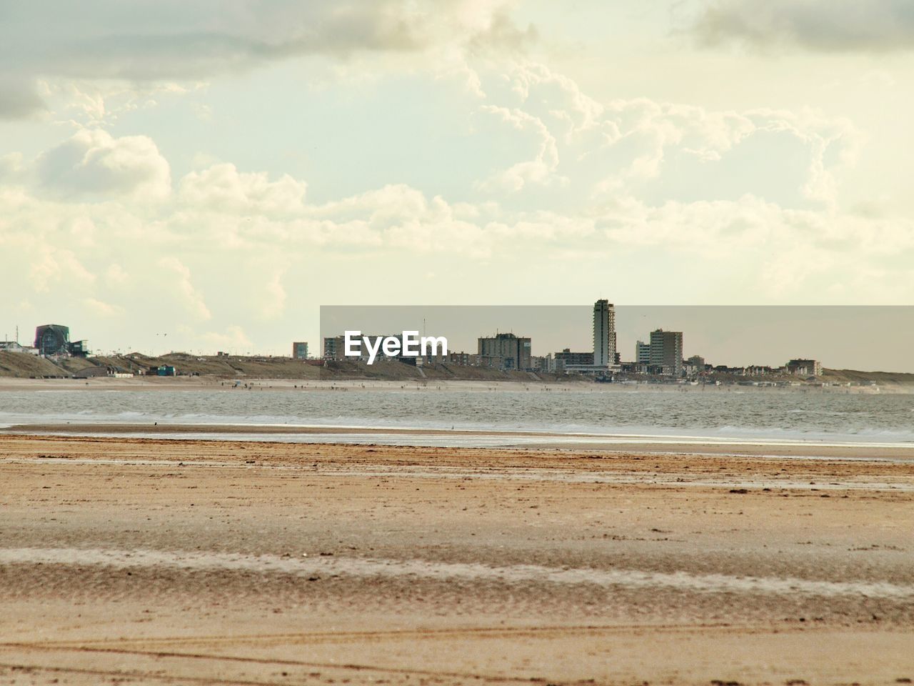 SCENIC VIEW OF SEA BY CITY AGAINST CLOUDY SKY