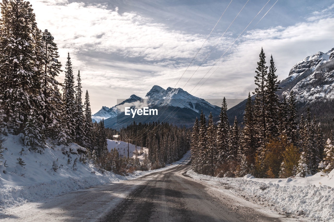 Road amidst snowcapped mountains against sky during winter