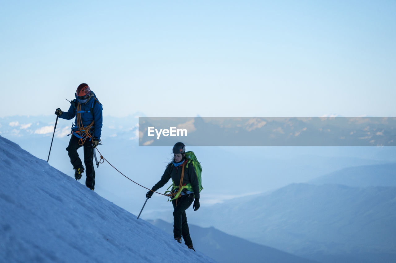 Two female mountaineers hike up a glacier on mt. baker, wa.